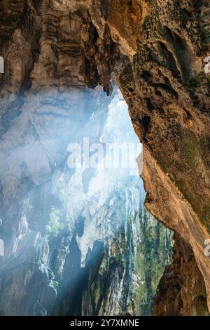 La lumière du soleil qui traverse l'ouverture de la grotte de Batu, illumine les formations rocheuses accidentées et jette une lueur mystique, créant une atmosphère sereine et mystérieuse Banque D'Images