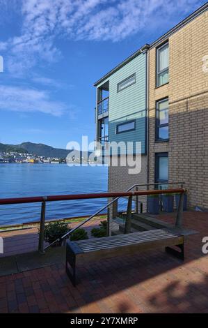 Bâtiment résidentiel moderne sur le front de mer avec vue sur la montagne sous un ciel bleu avec des nuages dispersés, Bergen, Vestland, Norvège, Europe Banque D'Images