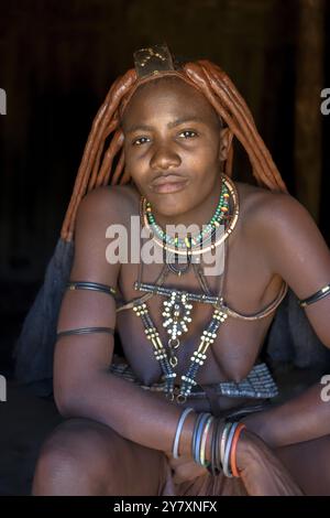 Jeune femme himba dans sa cabane, Ohandungu, région de Kunene, Kaokoveld, Namibie, Afrique Banque D'Images