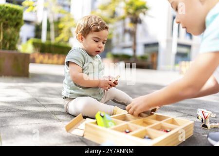 Gros plan de deux frères caucasiens jouant avec des jouets assis dans un parc urbain après l'école Banque D'Images