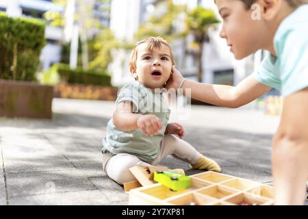 Gros plan d'une gêne caressant un bébé garçon jouant avec des jouets dans un parc Banque D'Images