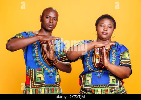 Homme et femme confiants montrant un geste de temporisation avec les mains et regardant la caméra. Couple afro-américain sérieux indiquant un signal d'arrêt, demandant à prendre un portrait studio de pause Banque D'Images