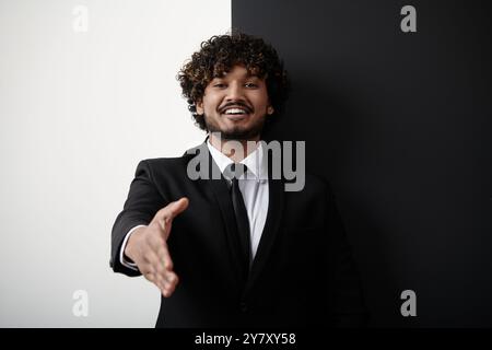 Heureux homme d'affaires indien étirant la main pour trembler sur fond noir et blanc Banque D'Images