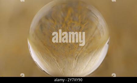 Gros plan d'une boule de verre qui reflète une structure jaune Banque D'Images