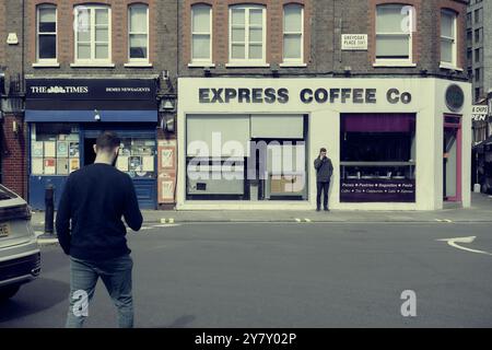 11 sep 2024 - Londres royaume-uni : deux hommes utilisant des téléphones portables dans une scène de rue à londres avec un espace de copie utilisant l'édition de couleurs délavées Banque D'Images