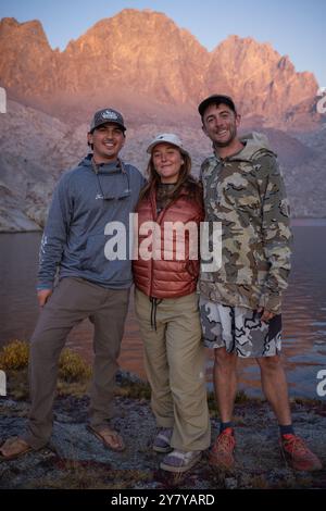 Trois cousins prennent une photo tout en admirant le coucher du soleil lors d'un voyage en sac à dos dans les Sierras orientales de Californie. Banque D'Images