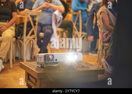 Un projecteur est sur une table devant un groupe de personnes Banque D'Images