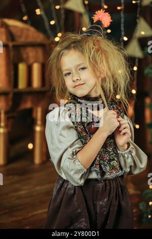 Une jeune fille debout devant un arbre de Noël décoré, l'air excitée et joyeuse. Banque D'Images