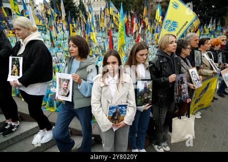 KIEV, UKRAINE - 01 SEPTEMBRE 2024 - les gens tiennent des pancartes sur la « pelouse de la mémoire nationale » recouverte de drapeaux portant les noms des héros tombés au combat pendant une minute de silence à la mémoire des soldats péris à l’occasion de la Journée des défenseurs de l’Ukraine, sur la place Maidan Nezalezhnosti, Kiev, capitale de l’Ukraine Banque D'Images