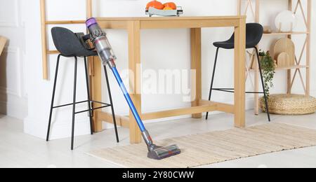 Un aspirateur sans fil reposant sur un tabouret à l'intérieur Banque D'Images