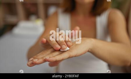 Femme appliquant la lotion sur ses mains dans un cadre de spa, affichant un accent sur le bien-être, la beauté et les soins de la peau dans un environnement intérieur, avec un calme et se Banque D'Images