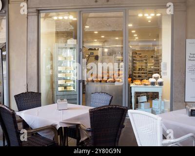 Mantoue, Italie 30 septembre 2024 les tables de café extérieures sont assis de manière vivifiante devant une boulangerie avec une vitrine de gâteaux et de pâtisseries et un travail de boulangerie Banque D'Images