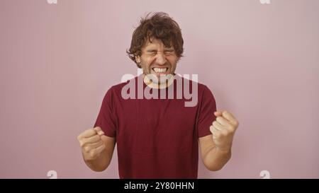 Portrait d'un jeune homme hispanique joyeux avec une barbe, portant une chemise marron sur un fond rose, exsudant la positivité. Banque D'Images