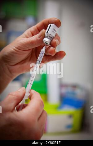 Vaccination contre le Covid-19 en pharmacie : un pharmacien prépare des doses de vaccins contre la grippe saisonnière et le covid19 pour la journée, un flacon d’ARNm de Comirnaty vac Banque D'Images