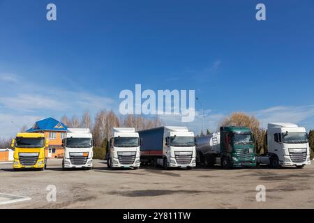 6 camions différents garés dans une rangée par une journée ensoleillée dans le parking. vue des cabines du tracteur Banque D'Images