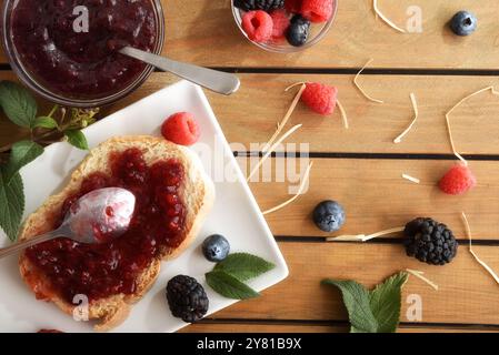 Pain grillé de confiture de baies maison sur l'assiette sur la table rustique avec des fruits et des feuilles. Vue de dessus. Banque D'Images