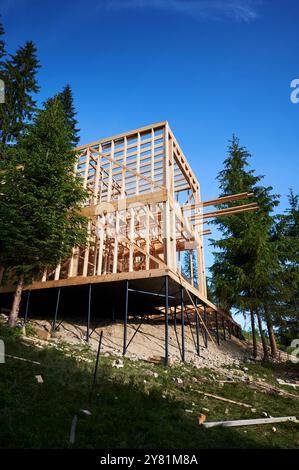 Bâtiment résidentiel avec ossature en bois en cours de construction près d'une forêt. Début de la nouvelle construction de chalet confortable. Idée de construction écologique, conception architecturale contemporaine Banque D'Images