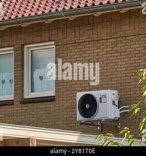 unité de pompe à chaleur à source d'air moderne montée sur le mur extérieur d'une maison, démontrant une technologie économe en énergie pour le chauffage et le refroidissement dans un susta Banque D'Images