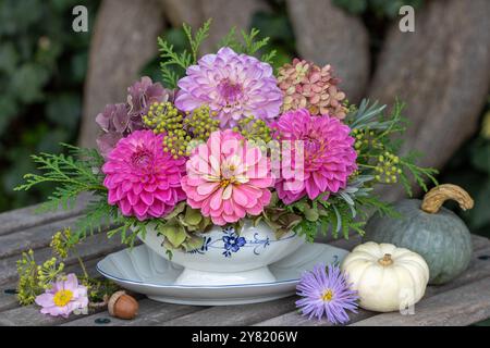 arrangement floral avec zinnia rose, dahlias, fleurs d'hortensia, fleurs de lierre et branches d'arborvitae dans un bateau de sauce dans le jardin Banque D'Images