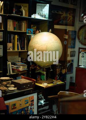 Un intérieur de magasin d'antiquités confortable rempli d'articles vintage assortis, de livres et d'un globe proéminent sur un stand. Banque D'Images