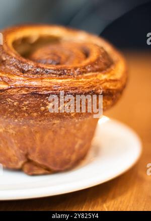 Petit pain à la cannelle sucrée gros plan servi sur une assiette, gros plan. Banque D'Images