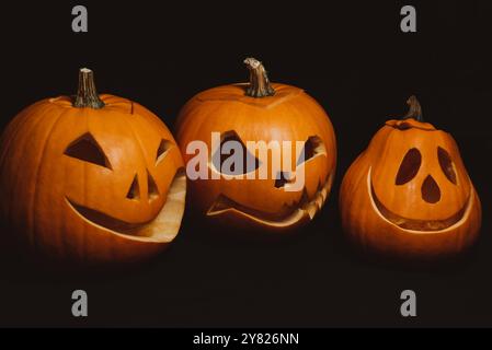 Citrouilles oranges aux visages sculptés pour la célébration d'Halloween. Lanterne de Jack sur fond noir Banque D'Images