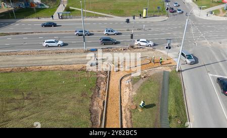 Vue aérienne d'un trottoir en construction avec ouvriers et équipement près d'une route. Banque D'Images