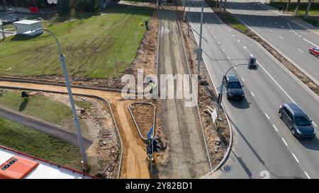 Vue aérienne d'un trottoir en construction avec ouvriers et équipement près d'une route. Banque D'Images