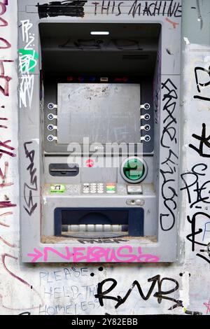 Un guichet automatique de caisse qui fonctionne semble négligé devant un magasin à Brick Lane, Londres. Banque D'Images