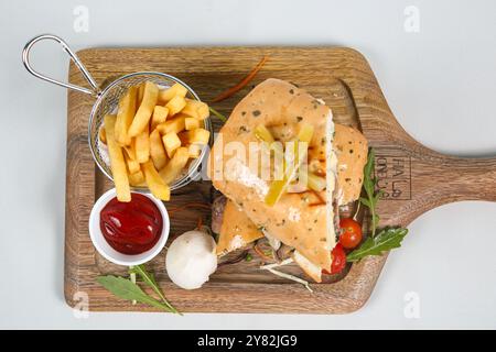 Sandwich au pastrami sur pain de seigle servi avec cornichons et sauce tomate. Sandwich savoureux avec pommes de terre frites sur fond blanc. vue de dessus Banque D'Images