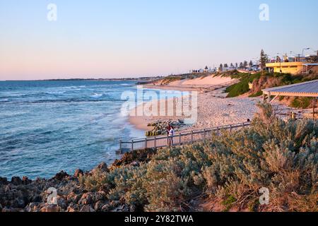 Mettams Pool au coucher du soleil avec végétation côtière et roches calcaires au premier plan, une plage à Perth, Australie occidentale. Banque D'Images