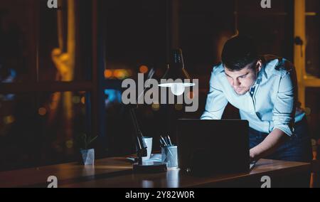 Homme d'affaires occupé travaillant sur ordinateur portable dans le bureau tard dans la nuit Banque D'Images