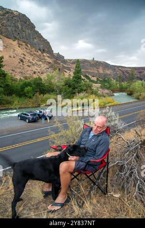 Mâle senior célibataire se détend avec son labo noir le long de la route 12 dans le canyon de la rivière Tieton à l'extérieur de Yakima, Washington Banque D'Images