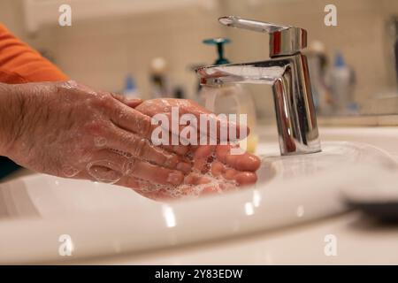Concept de journée mondiale du lavage des mains. Se laver les mains avec du savon sous le robinet d'eau avec de l'eau dans la salle de bain. Banque D'Images