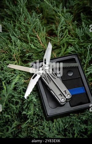 Couteau de poche MultiTool dans un étui ouvert sur verdure. Banque D'Images