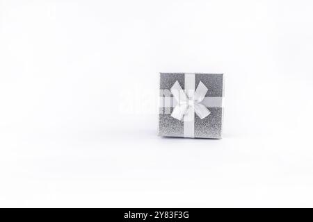 Petite boîte carrée décorative argentée avec arc blanc sur fond blanc pour cadeaux de Noël pour femme, pour mari, pour petite amie, pour petit ami Banque D'Images