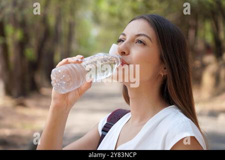 Bouchon attaché sur la bouteille en plastique. Gros plan d'une jeune femme buvant de l'eau à partir d'une bouteille en plastique avec un nouveau bouchon attaché pour encourager le recyclage, dans le cadre de th Banque D'Images