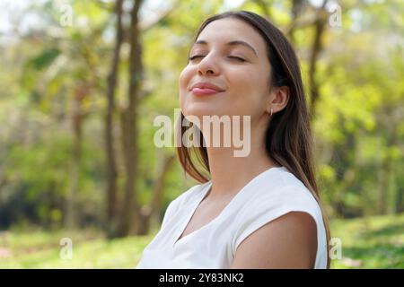 Belle jeune femme détendue respirant l'air frais dans un parc de la ville Banque D'Images