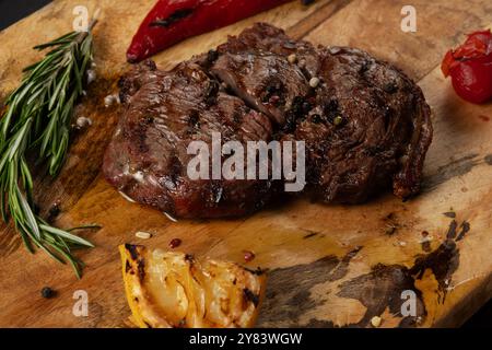 Grillé Rib Eye Black Angus servi avec du poivre et des herbes sur fond de bois. Banque D'Images