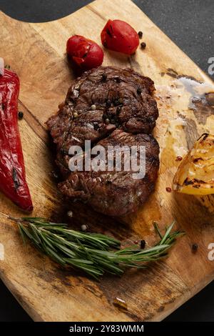 Tasty Rib Eye Black Angus servi avec du poivre et des herbes sur une planche de bois. Banque D'Images
