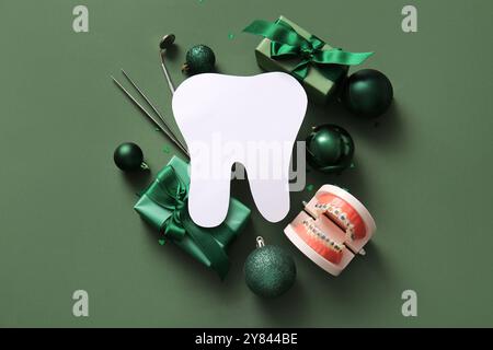 Composition avec dent en papier, outils de dentiste, cadeaux de Noël et décorations sur fond vert Banque D'Images
