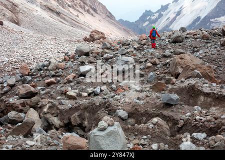 Le glacier glacé et les crêtes brunes du mont Kazbek se dressent devant vous alors qu'un grimpeur monte la montagne. Un terrain accidenté et difficile. Banque D'Images