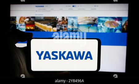 Dans cette illustration photo, une personne tient un téléphone portable avec le logo de la société japonaise Yaskawa Electric Corporation devant la page Web de l'entreprise. Banque D'Images