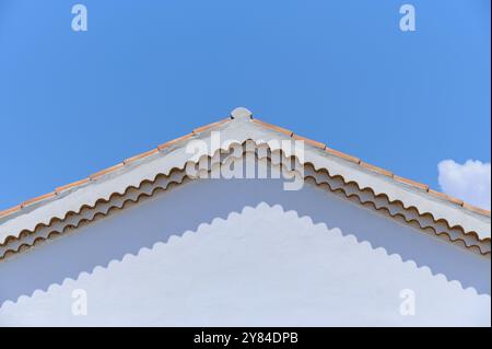 Haut d'une maison peinte en blanc avec un toit de tuiles rouges contre un ciel bleu clair, été, Saintes-Maries-de-la-mer, Camargue, France, Europe Banque D'Images