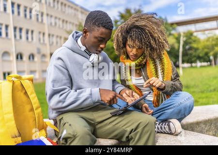 Étudiants accro à la technologie et à Internet assis à l'extérieur du campus en utilisant la tablette numérique Banque D'Images