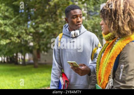 Étudiants multiraciaux en dehors du campus universitaire regardant le téléphone portable et parlant Banque D'Images