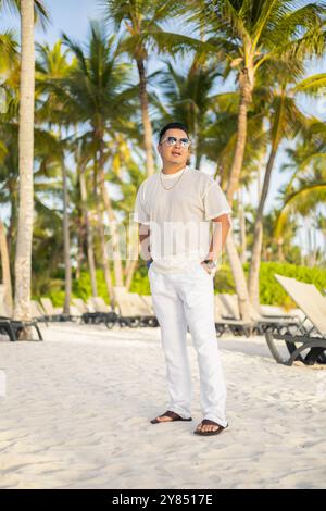 paysage tropical avec des palmiers, un jour ensoleillé, l'homme porte des lunettes de soleil, t-shirt et pantalon, portrait de jeune personne, mannequin masculin, style de vie Banque D'Images