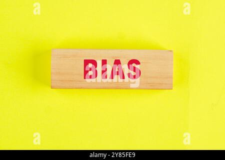 Concept de faits et de préjugés. Un mot BIAS écrit sur des blocs de bois avec un fond jaune-vert Banque D'Images