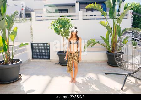 Une jeune femme en bikini profite d'un casque VR dans un cadre tropical luxuriant plein de verdure Banque D'Images