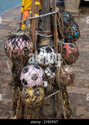 Une collection de vieux flotteurs / bouées de pêche en mer fabriqués à partir de ballons de football en plastique et de filet en maille accroché sur le quai d'Ives Harbour, Cornwall, Angleterre, Royaume-Uni Banque D'Images